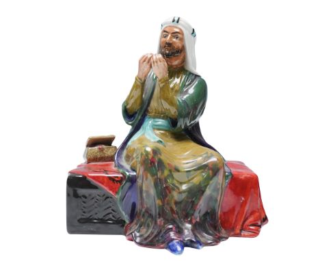 This hand-painted ceramic sculpture portrays a seated merchant figure dressed in traditional attire with a wrapped turban and