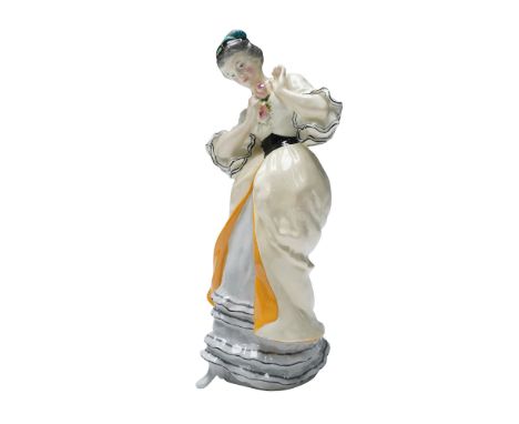 The figure is dressed in a cream gown with orange interior panels and black trim on the sleeves. She wears a grey underskirt 