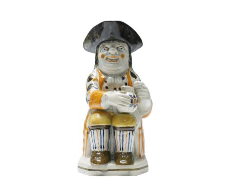 Early English pearlware Toby jug depicting a seated man holding a mug of ale, modeled in traditional form. The figure is dres