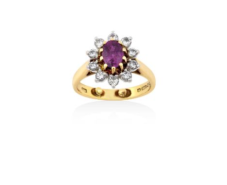 An 18 Carat Gold Ruby and Diamond Cluster Ringthe oval cut ruby in a yellow claw setting, within a border of round brilliant 