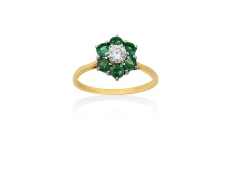 An 18 Carat Gold Emerald and Diamond Ringthe central raised round brilliant cut diamond within a border of round cut emeralds