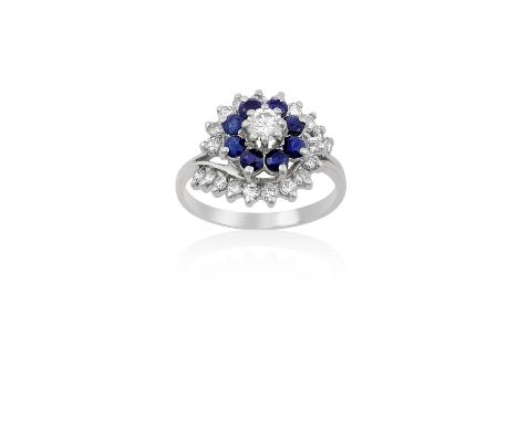 An 18 Carat White Gold Sapphire and Diamond Cluster Ring the central round brilliant cut diamond within a border of round cut