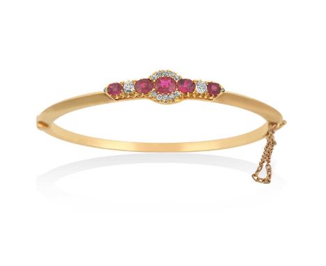 A Ruby and Diamond Hinged Banglethree oval cut rubies flanked by an old cut diamond and a round cut ruby, the central ruby wi