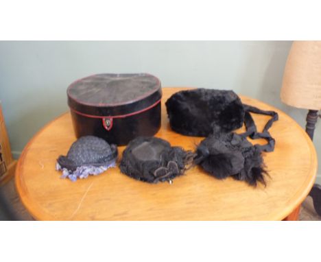 A vintage black hat box containing Victorian lady's hats and a muff