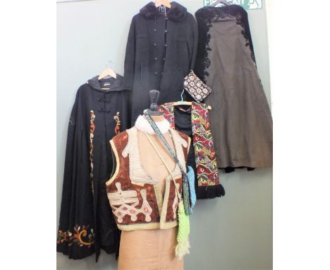A collection of vintage clothing including a velvet cap, heavily embroidered waistcoat, evening dress, handbags, neck cuff et
