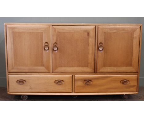 An Ercol Windsor style elm sideboard, with three cupboard doors and two drawers below, 129cm by 43cm by 76cm