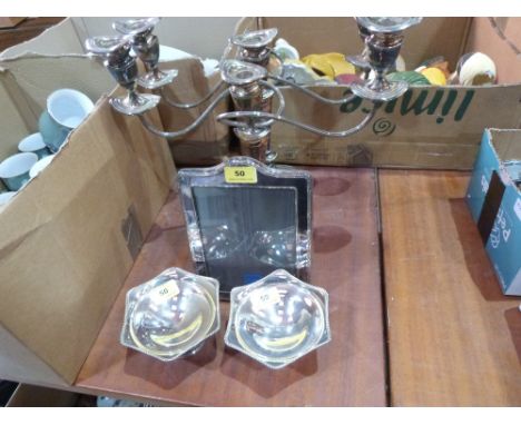 A pair of plated three light candelabra, a pair of plated bonbon dishes and a photograph frame