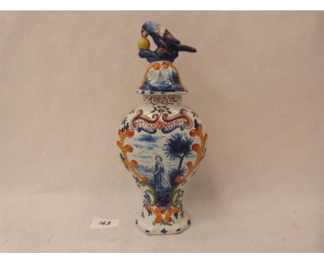 A 19th century faience inverted baluster vase, the domed cover with parrot finial. 11' high