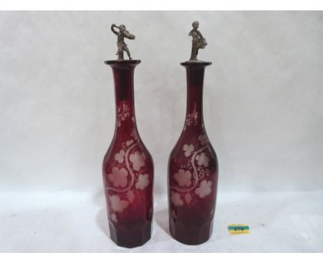 A pair of ruby glass decanters with figural stoppers with acid etched vine fruit decoration. 12' high. One with rim chips