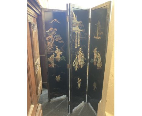 A Japanese black lacquered four panel room screen, decorated in light relief with women in a garden, character marks verso, e