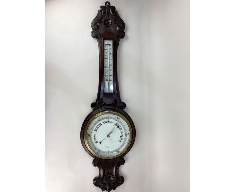 An early 20th century carved walnut banjo barometer and thermometer, makers name worn off dial, (brass mount a/f) 90cm