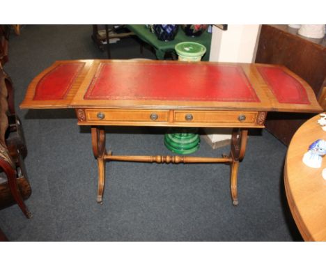 A modern mahogany sofa table, with red leather inset top above two drawers, on lyre shaped supports and outswept legs to bras