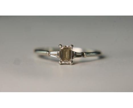 A boxed Art Deco style platinum and diamond flanked solitaire ring. Set to centre with a 0.51 carat emerald cut diamond, F co