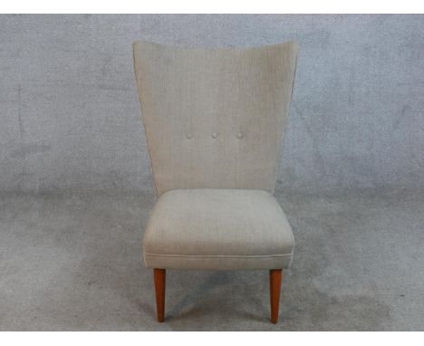 A mid 20th century Danish teak framed nursing chair with button back upholstery, raised on four splayed tapering supports. 