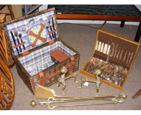 A pair of brass fire dogs, fire side utensils, vintage picnic basket and a small canteen of cutlery