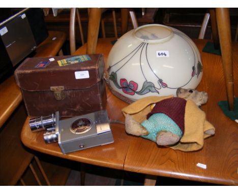 A vintage G. B. Bell & Howell 16mm film camera in brown leather case, a Teddy Bear and ceiling lightshade  