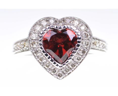 A garnet and diamond set dress ringThe heart shaped garnet to a round brilliant cut diamond surround, in 9k white gold, ring 