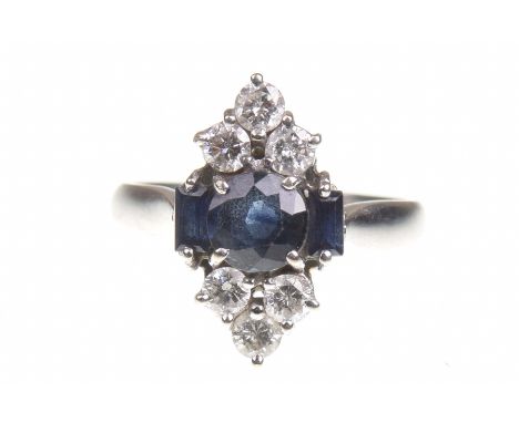 A sapphire and diamond dress ringThe circular shaped sapphire, flanked by two sapphire baguettes, highlighted by round brilli