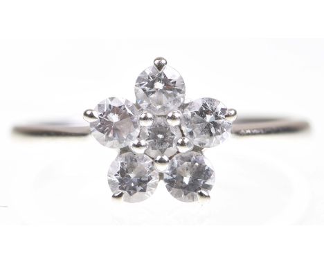 A diamond cluster ringDesigned as a flowerhead, centring a round brilliant cut diamond to a round brilliant cut diamond surro