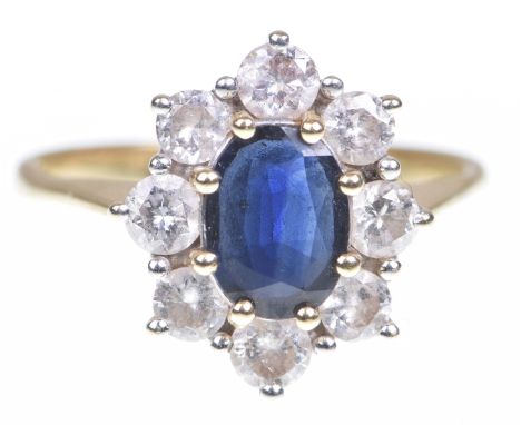 A sapphire and diamond cluster ringThe oval shaped sapphire to a round brilliant cut diamond surround, 18k gold shank, total 