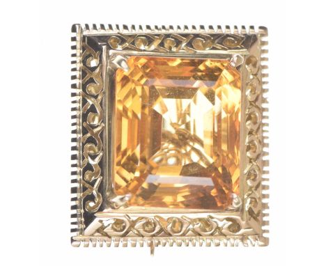 A citrine brooch The step cut citrine set to a pierced rectangular surround, with safety chain, to a precious yellow metal mo