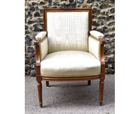 A French Louis XVI style bergère armchair, with moulded frame, the backrest with central carved bow floral detail, scroll end