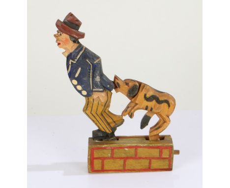 Carved wooden and painted toy in the form of a man and dog, with press button action, 19cm high