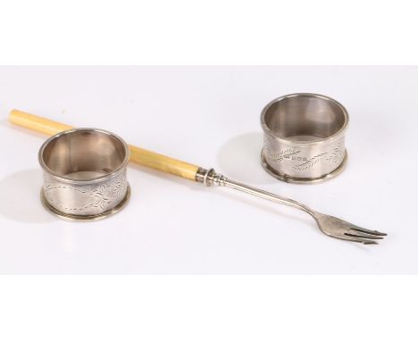 Pair of George V silver serviette ring, Birmingham 1938, each with foliate engraving, and a silver pickle fork, Sheffield 191