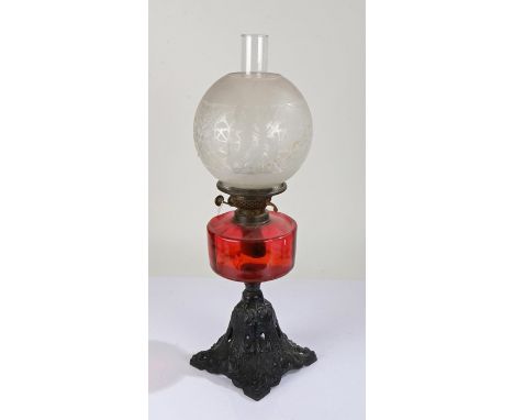 Best British Make oil lamp, the frosted foliate etched globe above a ruby glass reservoir and pierced metal foot, 58cm high