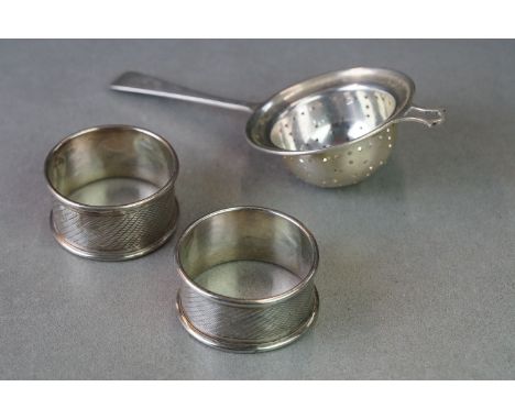 A small group of fully hallmarked sterling silver collectables to include napkin rings and a tea strainer. 