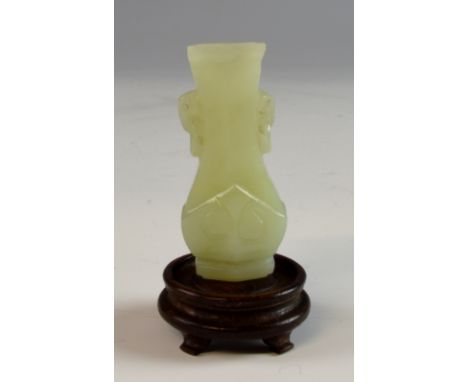 Chinese pale celadon jade carved vase with twin elephant mask handles, 5cm high, with non-matching wooden stand.   