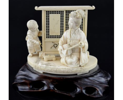 Japanese carved ivory okimono of a mother and child before a sliding screen. 13cm wide, 10cm high, on hardwood base,PLEASE NO