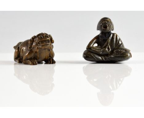 Horn netsuke of a seated figure, 3.5cm x 4cm, and a carved wood netsuke of a temple lion 2.5cm x 4cm.   