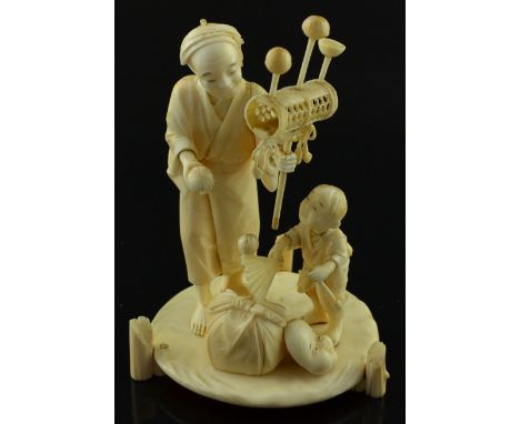 19th century Japanese carved ivory figure of a travelling entertainer and his son on a round base, Meiji period, signed on ba