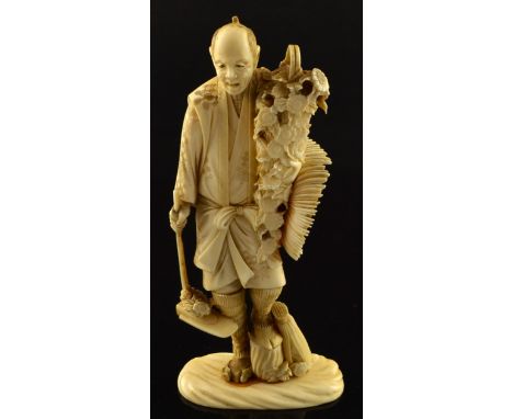 19th century Japanese carved ivory okimono, a gardener with a spade in one hand with a basket of trailing flowers over his sh