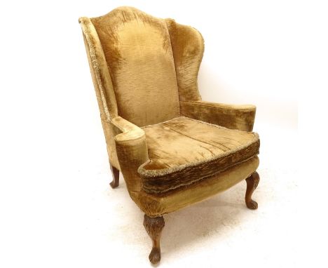 A reproduction button-back fireside armchair, on walnut cabriole legs 