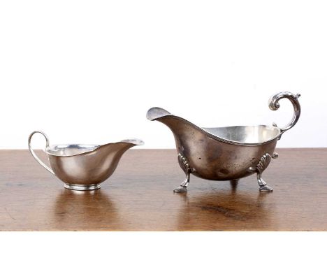 Two silver sauce boats the larger example standing on three feet, with scroll capped handle, bearing marks for William Hutton