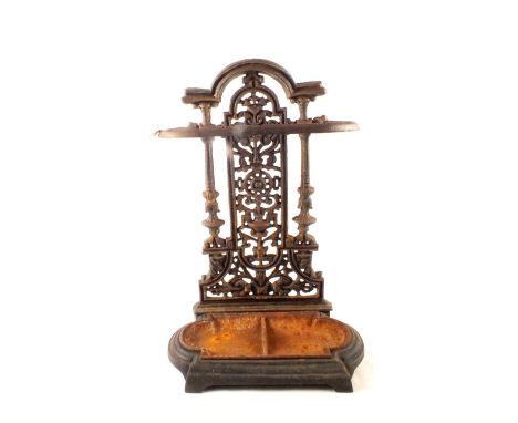 A late Victorian cast iron stick stand with decorative open work back plate having arched top and the shaped base with lift o