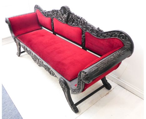 A large 19th century ebony sofa (possibly Ceylonese): the high central carved scallop-shell-style ornament flanked by leaves,