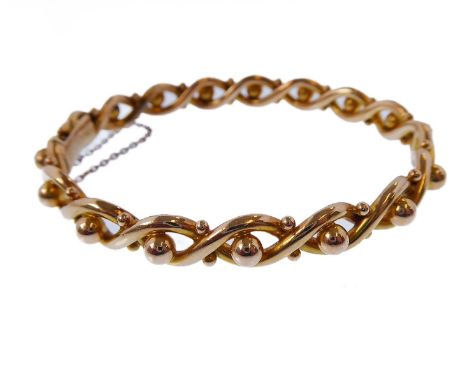 A late Victorian hinged bangle of yellow gold (untested) entrelac and sphere design, the clasp engraved 'Rd 147858' for 1890/