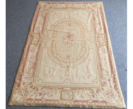 A French Aubusson tapestry: predominately light-cream ground, central bouquet of flowers within an oval and surrounded by a b