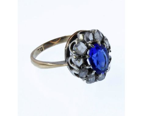 A lady's 9-carat yellow gold dress ring centrally-set with a hand-cut oval blue stone (untested) of pleasing colour and surro