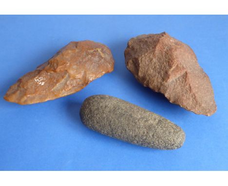 A polished Neolithic stone axe head, one other similar slightly larger unpolished and a rounded stone axe head (the largest 1