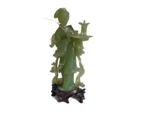 A carved Chinese light-green hardstone standing female figure, in her left hand she holds an oval tray with ritualistic style