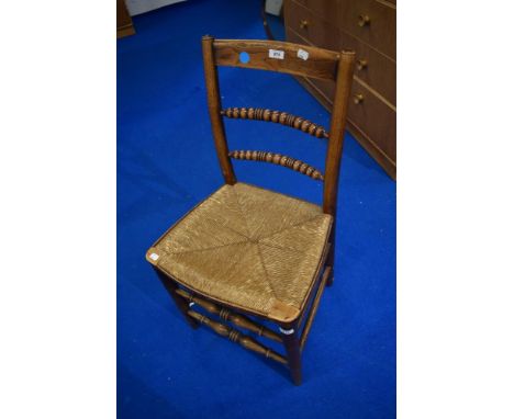 A 19th Cetury oak framed bobbin back kitchen chair with rush seat and a later cane seated carver chair