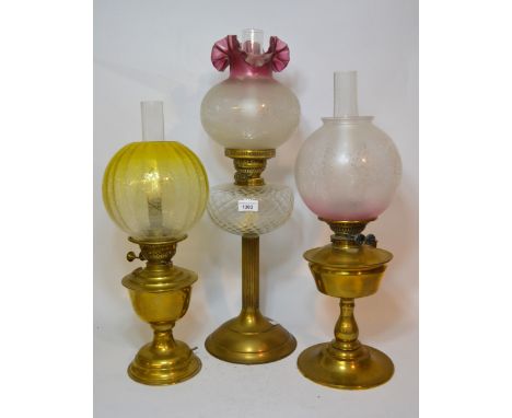 Edwardian brass oil lamp with an etched and tinted glass shade, together with two other similar oil lamps, one with a cranber