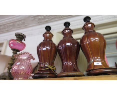 Three matching pottery brown glazed floral decorated lamp bases and an oil lamp with glass well and shade 