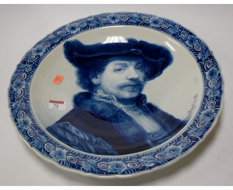 An early 20th century Joost Thooft & Labouchere Dutch Delft charger, decorated with a portrait after Rembrandt within a flora