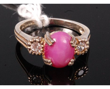 A silver gilt, ***SYNTHETIC***ruby and diamond set dress ring, the four claw set cabochon flanked to either side by single il