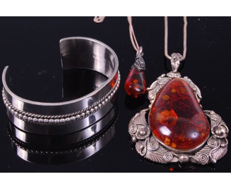 A large teardrop shaped amber pendant, within white metal leaf surround and on meshlink necklace; together with one other whi